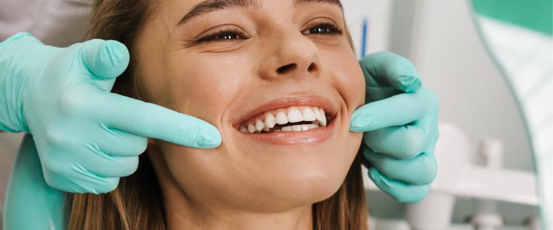 A girl smiles while being treated by an orthodontist