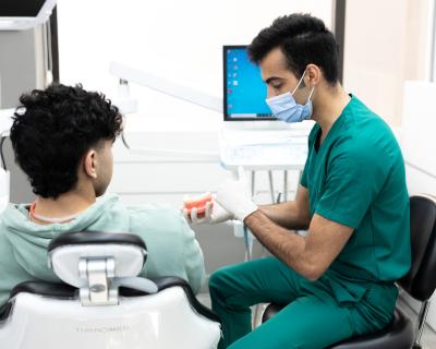 Dentist educating male patient about what is IPR and clear aligner treatment.  