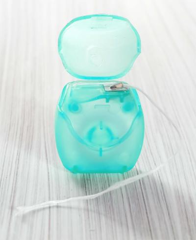 dental tape floss with thin nylon fibers in a green case 